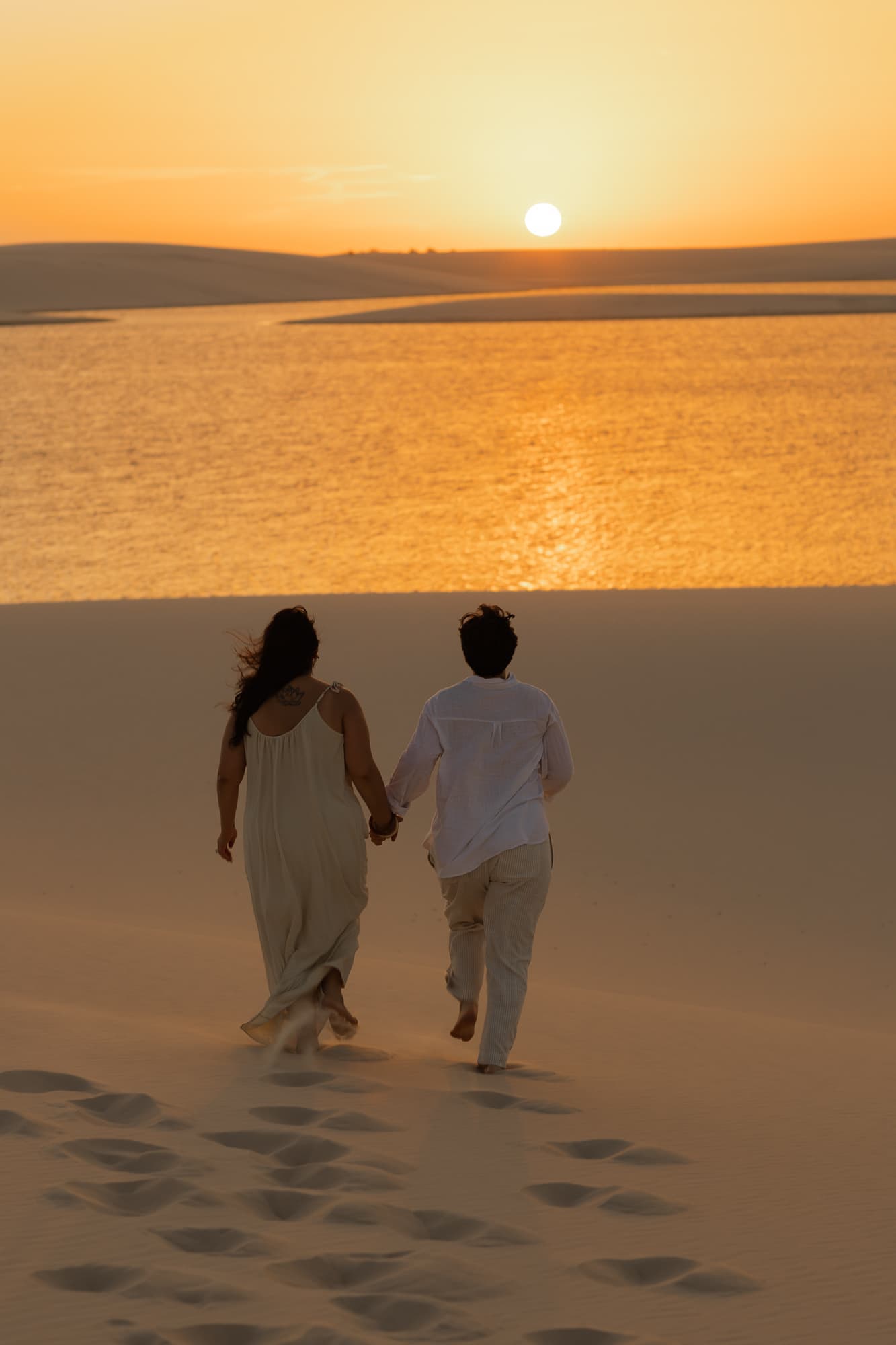 Amana e Julie, caminhando de mãos dadas nas dunas, Santo Amaro, Lençóis Maranhenses