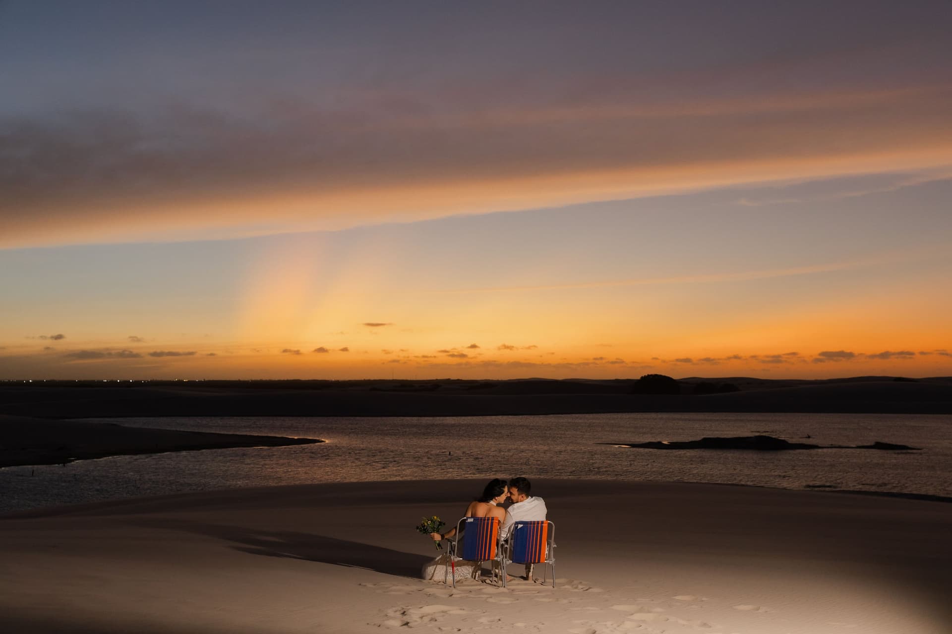Casal ao pôr do sol nas dunas altas de Santo Amaro, Lençóis Maranhenses