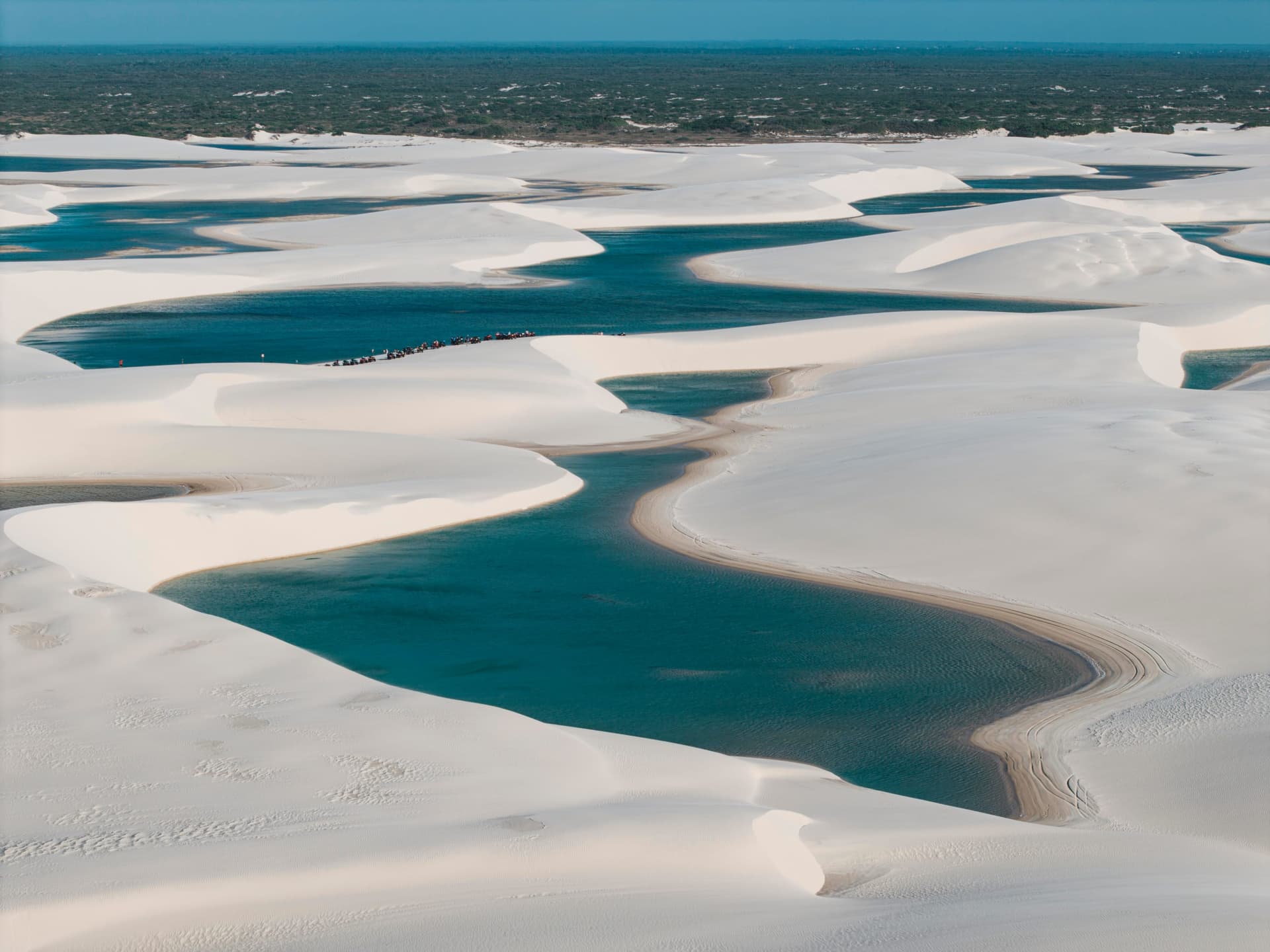 Field of dunes and blue lagoons in Atins with visitors in the distance, Lençóis Maranhenses