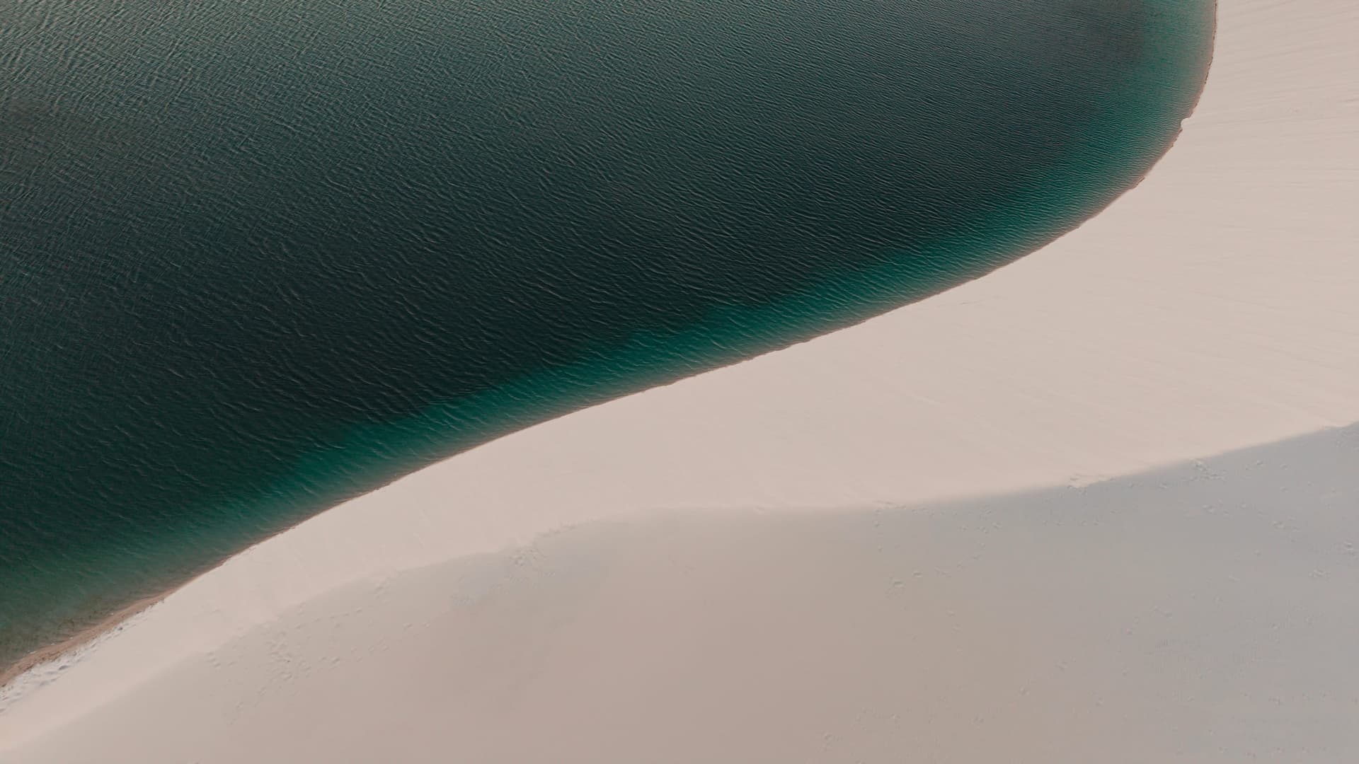 Minimalist curve between the green lagoon and the white dune in Santo Amaro