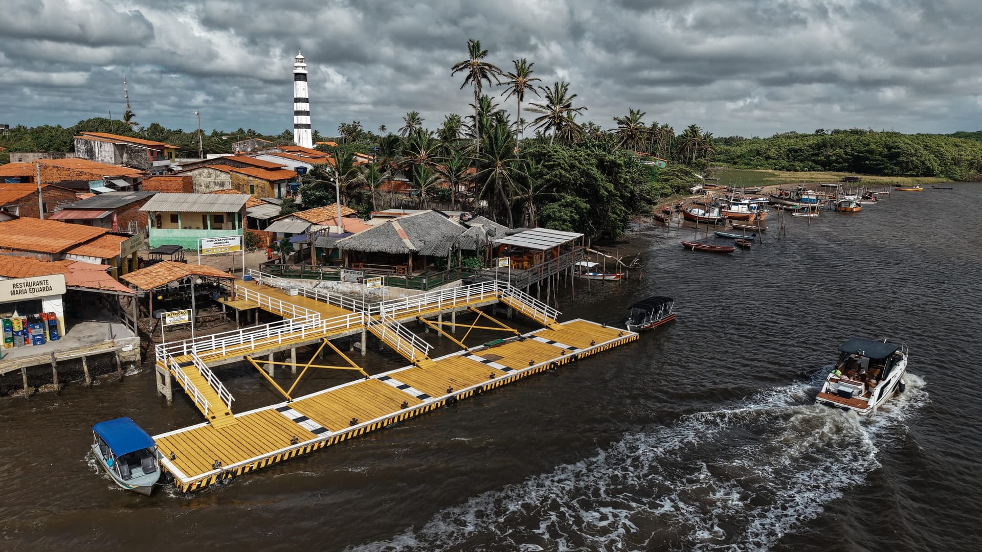 Mandacaru port with the Preguiças Lighthouse among palm trees, on the banks of the Preguiças river